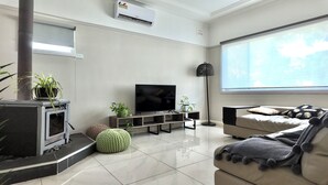 Ein modernes Wohnzimmer mit Flachbildfernseher, einer Couch, einem Couchtisch und einem Kamin.