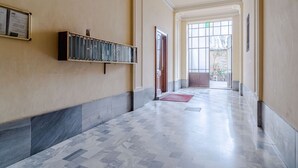 Un couloir avec un sol carrelé, un banc en bois et une porte donnant sur une autre pièce.