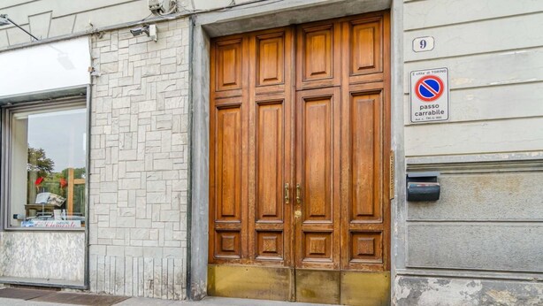 Un bâtiment doté d’une grande porte à double battant en bois, d’une fenêtre qui reflète la lumière et d’un panneau indiquant qu’il est interdit de se garer.