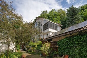 A modern two-story house with a garden, a wooden fence, and a solar panel on the roof.