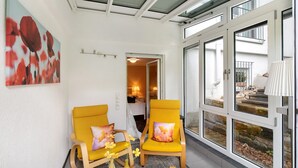 A room with two yellow chairs, a glass door leading outside, and a painting on the wall. - Apartment 'Burgblick' with Shared Garden and Wi-Fi (Bad Urach)