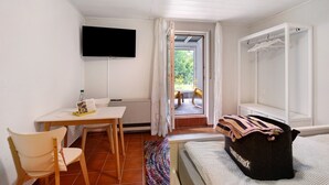 A room with a bed, a desk, a chair, a television, and a view of the outside. - Apartment 'Burgblick' with Shared Garden and Wi-Fi (Bad Urach)