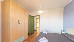 A bedroom with a bed, a wardrobe, and a door leading to another room.