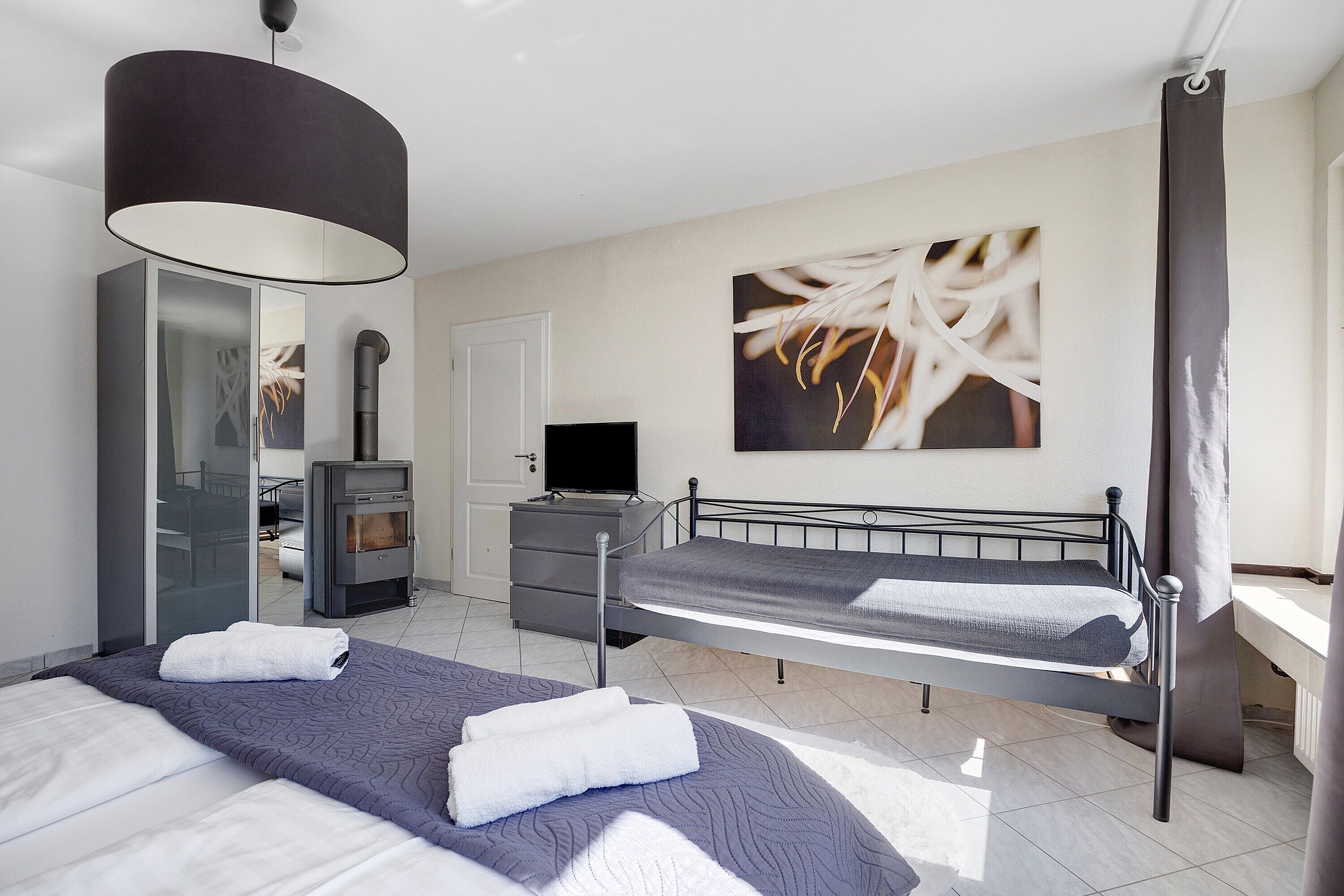 A bedroom with two beds, a TV, a wardrobe, and a fireplace.