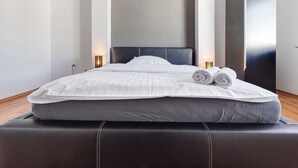 A modern hotel room with a large bed, a headboard, bedside lamps, and a wardrobe.
