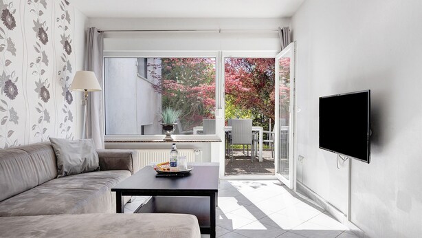 A modern living room with a sofa, a coffee table, a lamp, and a TV.