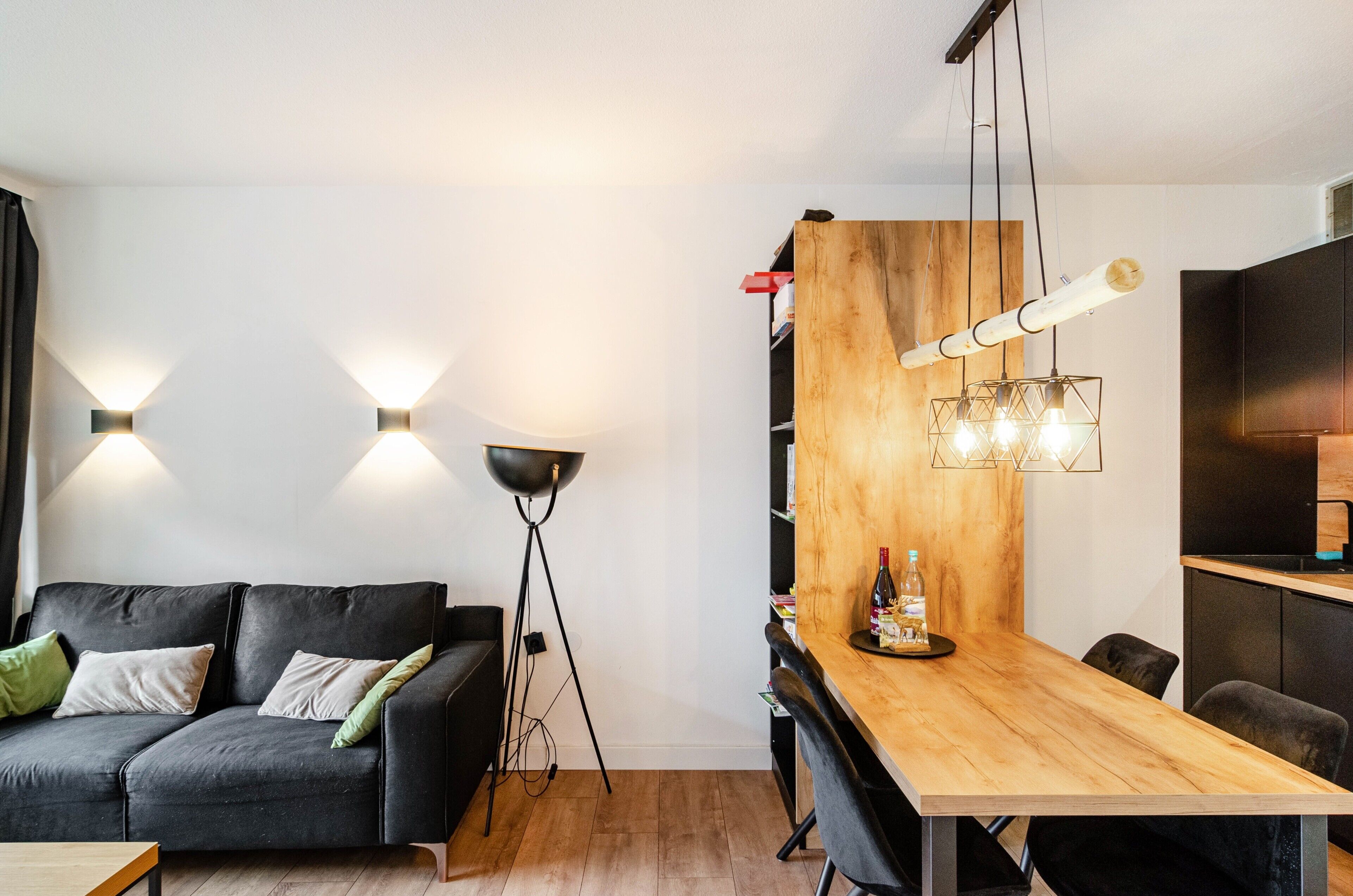 A modern living space with a sofa, a dining table, and a kitchen area.