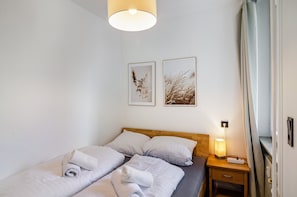 A hotel room with two beds, a bedside table with a lamp, and two framed pictures on the wall. - Design Apartment with Shared Garden, Balcony, and Wi-Fi in Goslar (Goslar)