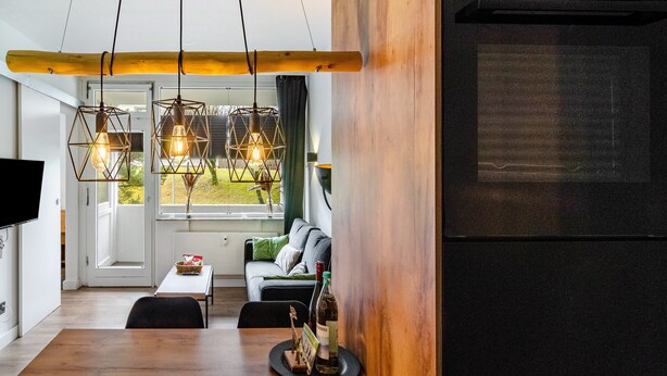 Una cocina moderna con refrigerador Bosch empotrado, detalles de madera e iluminación colgante.