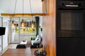 A modern kitchen with a built-in Bosch refrigerator, wooden accents, and pendant lighting. - Design Apartment with Shared Garden, Balcony, and Wi-Fi in Goslar (Goslar)