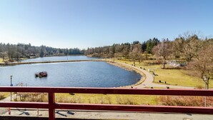Vista de un lago con un sendero curvo, una pequeña isla y un edificio distante.
