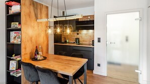 Una cocina moderna con una mesa de comedor de madera, sillas negras y una lámpara colgante.
