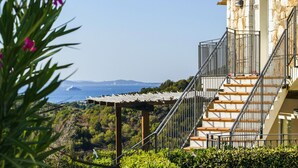A stone building with a staircase leading to a balcony overlooking a coastal area.