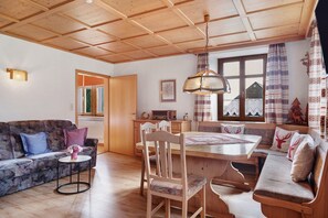 Une pièce chaleureuse avec un plafond en bois, un canapé, une table à manger et un banc.