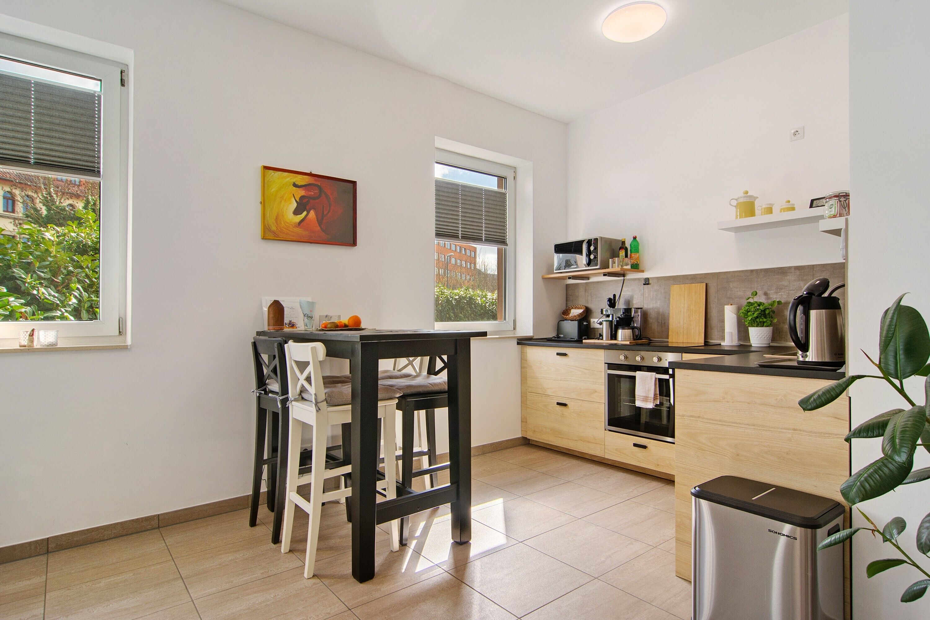 A modern kitchen with a dining area, large windows, and a view of the outside.