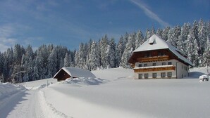 A snow-covered lodge with a wooden exterior and a sloped roof, surrounded by snow-laden trees.