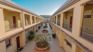 A corridor with multiple balconies, potted plants, and a central garden area.