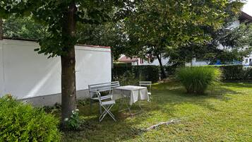 Un'area verde all'aperto con un muro bianco, una panchina e un tavolo.