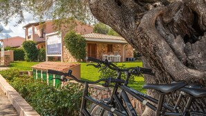 Una bicicleta estacionada frente a un edificio con fachada de piedra y un letrero que dice "RESIDENZE GALLURA".