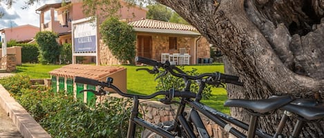 A bicycle parked in front of a building with a stone facade and a sign that reads "RESIDENZE GALLURA".