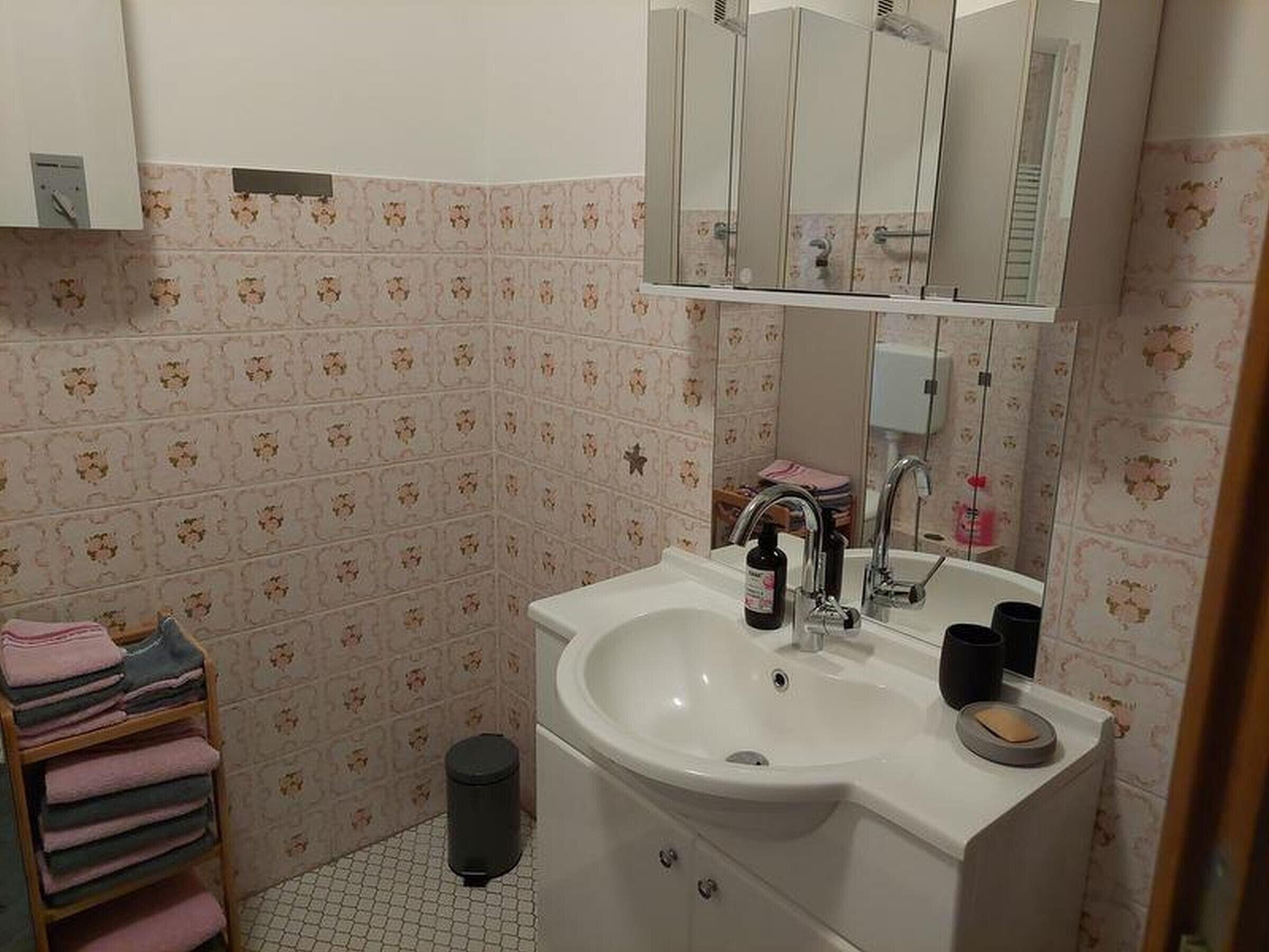 A bathroom with a sink, mirror, and tiled walls.
