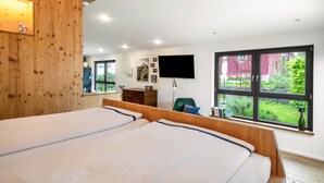 Une chambre avec deux lits, des murs en bois, une télévision et une fenêtre donnant sur un paysage verdoyant.