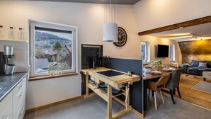 Eine moderne Küche mit einer Holzinsel, einem großen Fenster und einem Essbereich mit einer Couch.