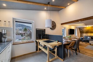 A modern kitchen with a wooden island, a large window, and a dining area with a sofa.