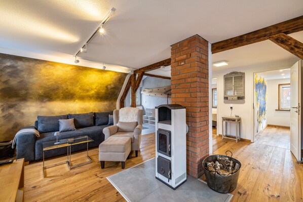 Una sala de estar acogedora con sofá, sillón, chimenea y vigas de madera.