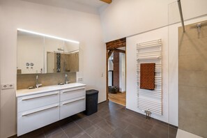 Un baño moderno con un espejo grande, tocador blanco y un perchero para toallas.