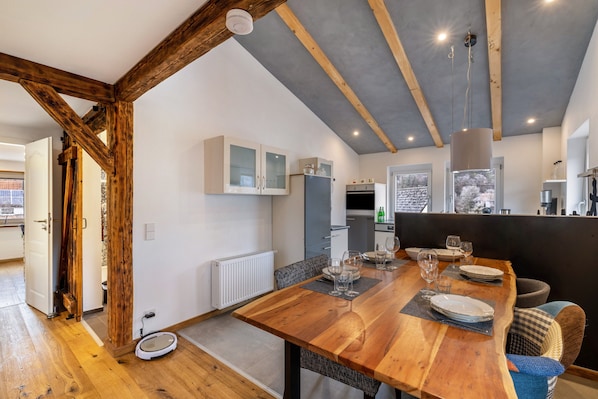 Un comedor con mesa de madera, sillas y techo con vigas a la vista.