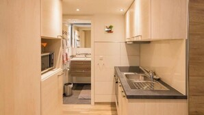 Een kleine keuken met houten kastjes, een roestvrijstalen spoelbak en een magnetron.