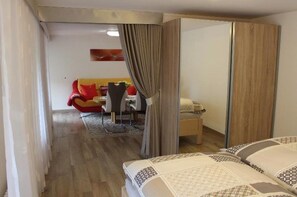Una camera d'albergo con un letto, una zona pranzo con una sedia rossa e un armadio in legno.