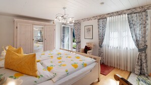 A bedroom with a bed, a chair, a mirror, and a window with curtains. - Gartenblick Apartment with Private Terrace, Shared Garden and Wi-Fi (Enzklösterle)