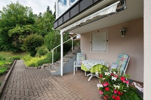 Un patio con una mesa y sillas, una escalera y un jardín.