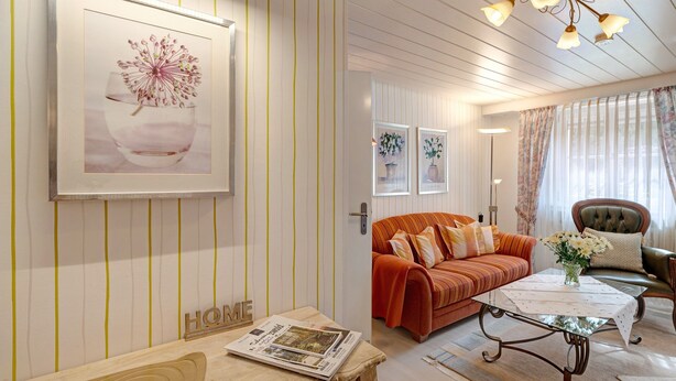 A living room with a striped wall, a sofa, a coffee table, and a framed picture. - Gartenblick Apartment with Private Terrace, Shared Garden and Wi-Fi (Enzklösterle)