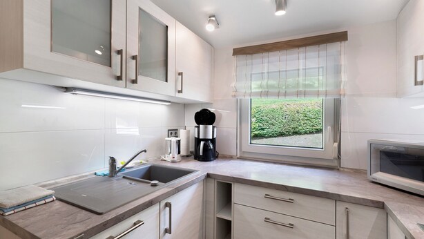 Una cucina moderna con forno a microonde integrato, una macchina del caffè e una finestra vista verde.