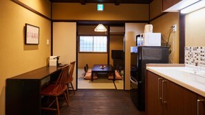 A compact kitchen with a dining area, wooden cabinets, a refrigerator, and a small TV.