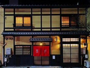 A traditional Japanese building with a tiled roof, wooden lattice windows, and a red awning. - Miro Matsubara Takaseigawa Tei North (Kyoto)