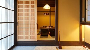 A traditional Japanese room with tatami flooring, a low table with cushions, and a sliding door.