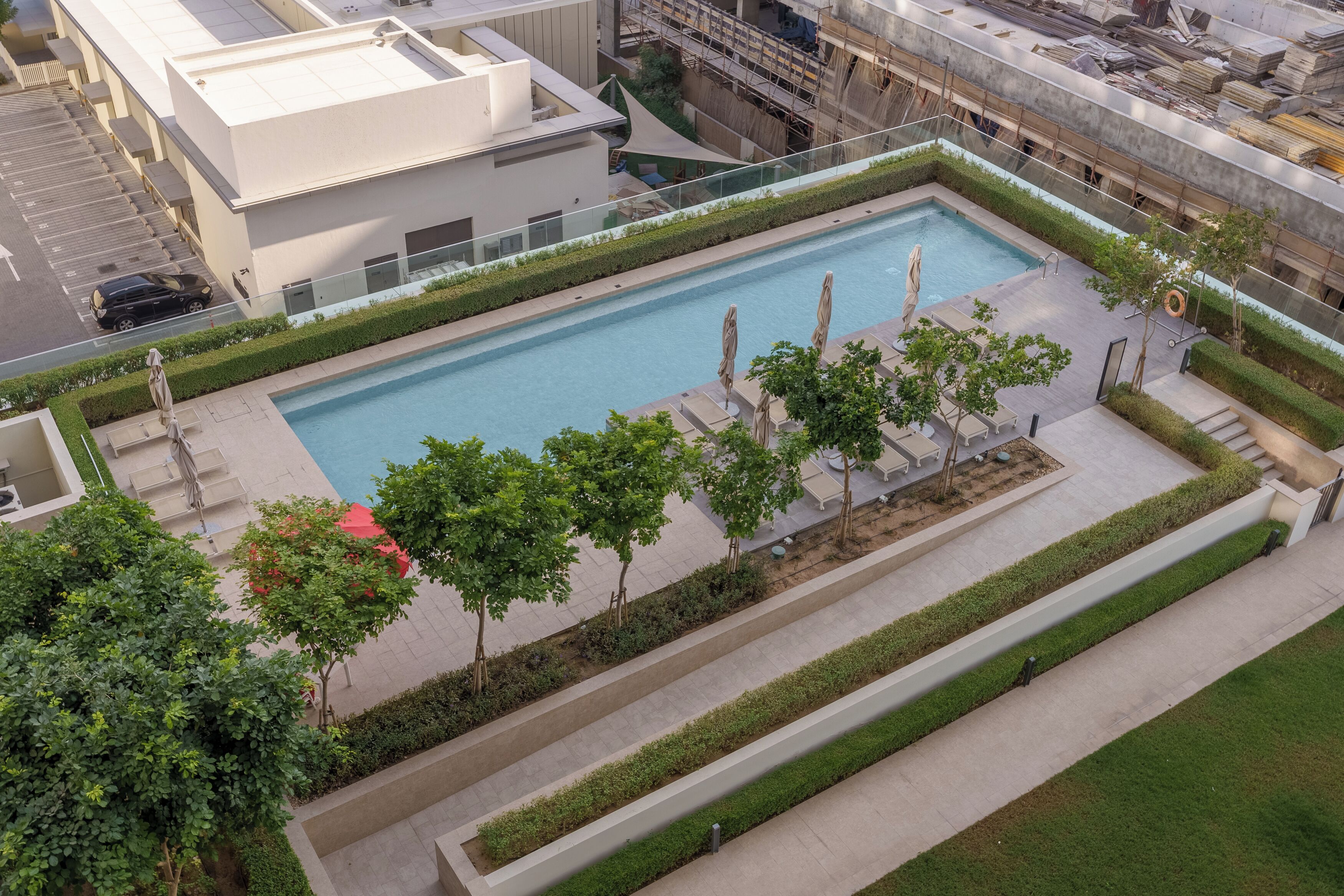 Ein Luftbild eines modernen Hotels mit rechteckigem Pool, umgeben von ordentlich geschnittenen Hecken und Bäumen.