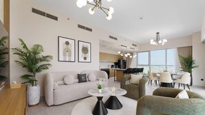 A modern living room with a sofa, a coffee table, and a dining area with chairs. There are plants and artwork on the walls. - Maison Privee - Tranquil Living with Golf Course Vws in Dubai Hills (Dubai)