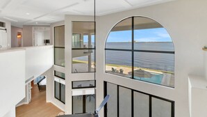 A modern interior with a large arched window overlooking a body of water. - Luxury River View Estate | Heated Pool & Amazing Sunsets | Perfect Gathering for Families & Friends (Fort Myers)