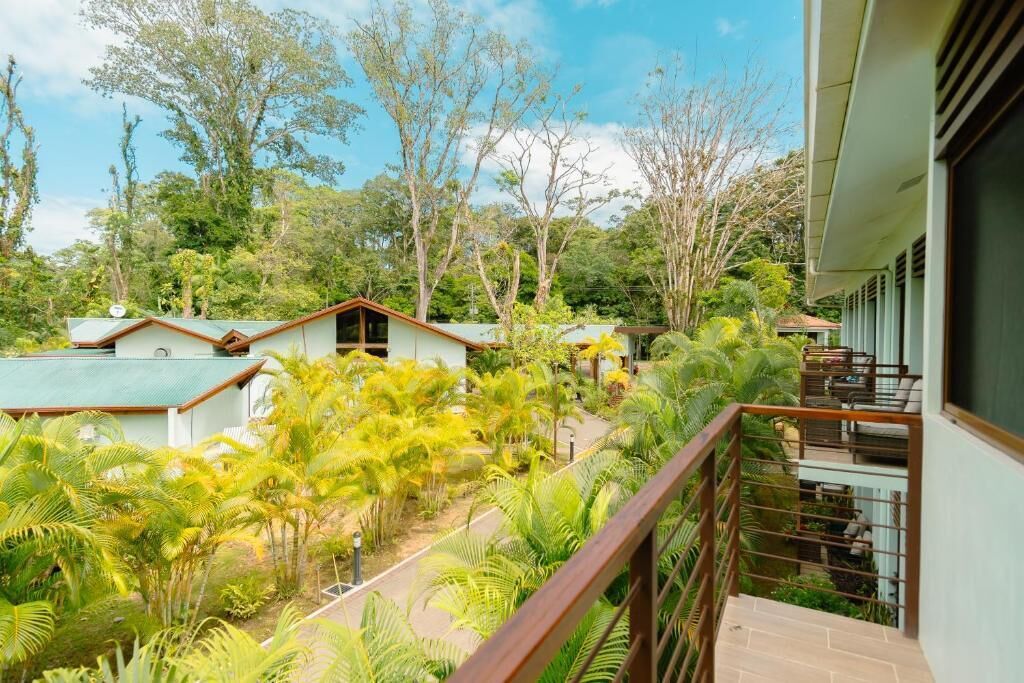 Un hôtel composé de plusieurs bâtiments, entouré d’une végétation luxuriante, notamment de palmiers et d’autres plantes tropicales.