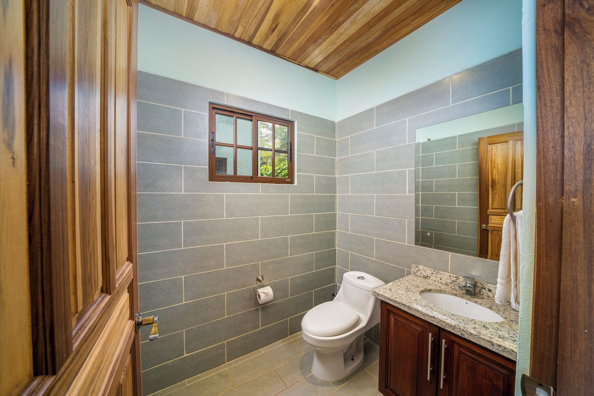 Een badkamer met toilet, wastafel en raam.