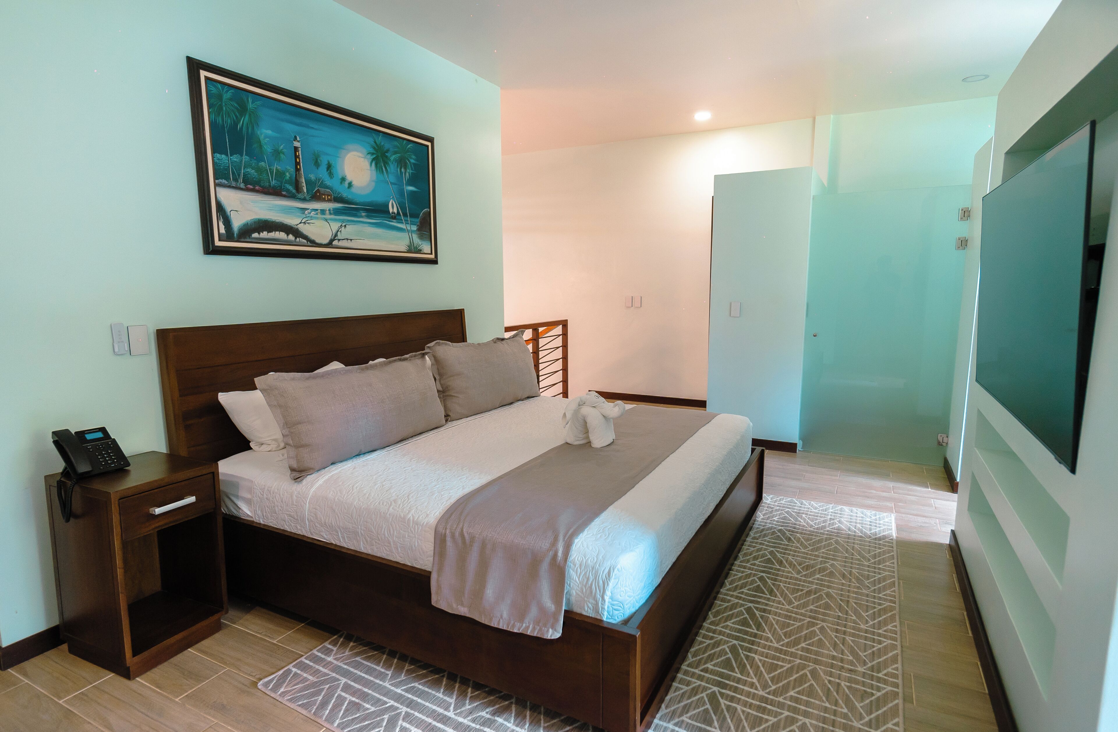 A bedroom with a bed, nightstand, and a painting on the wall.