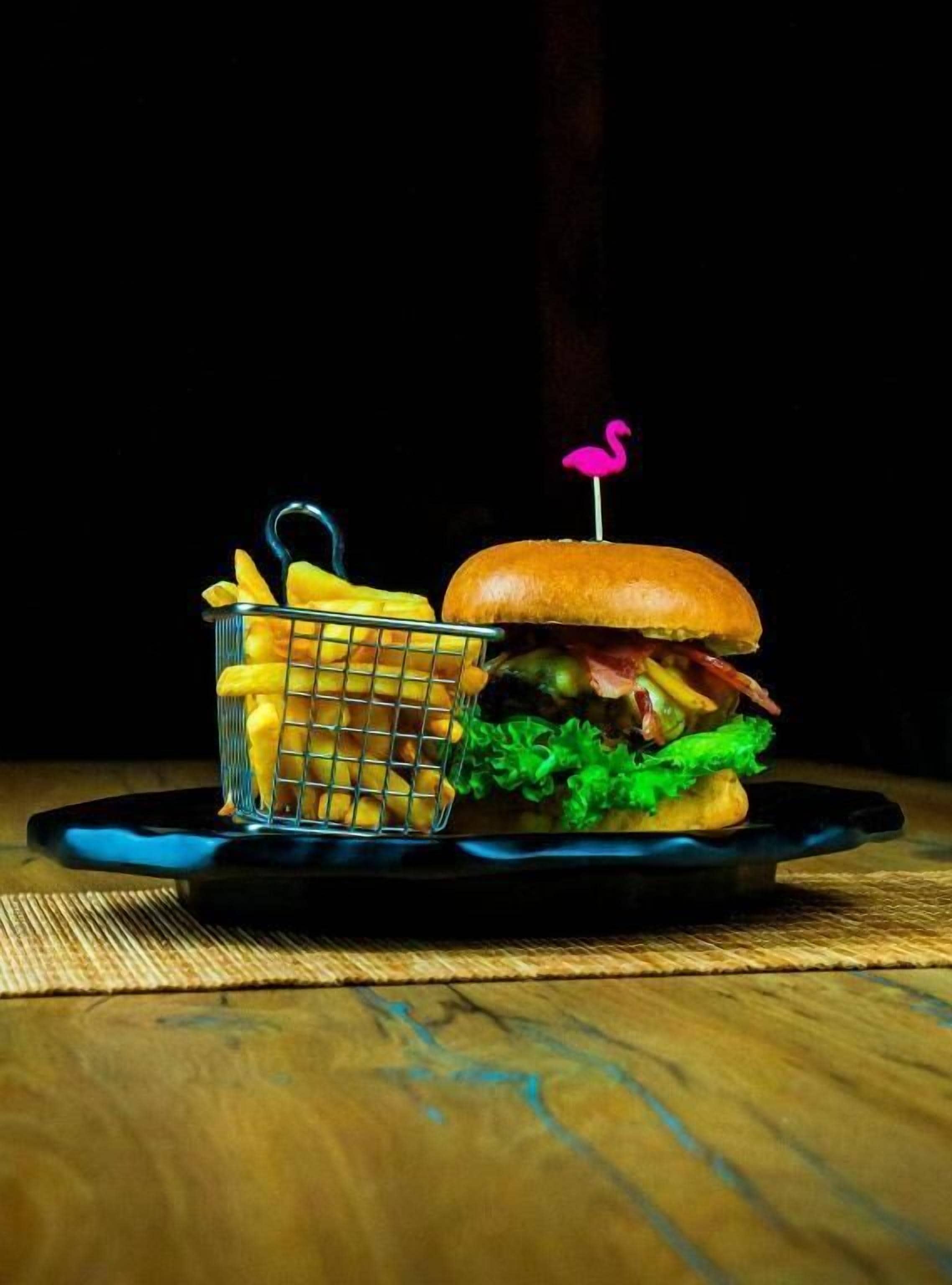 A meal with a burger and fries on a black plate.