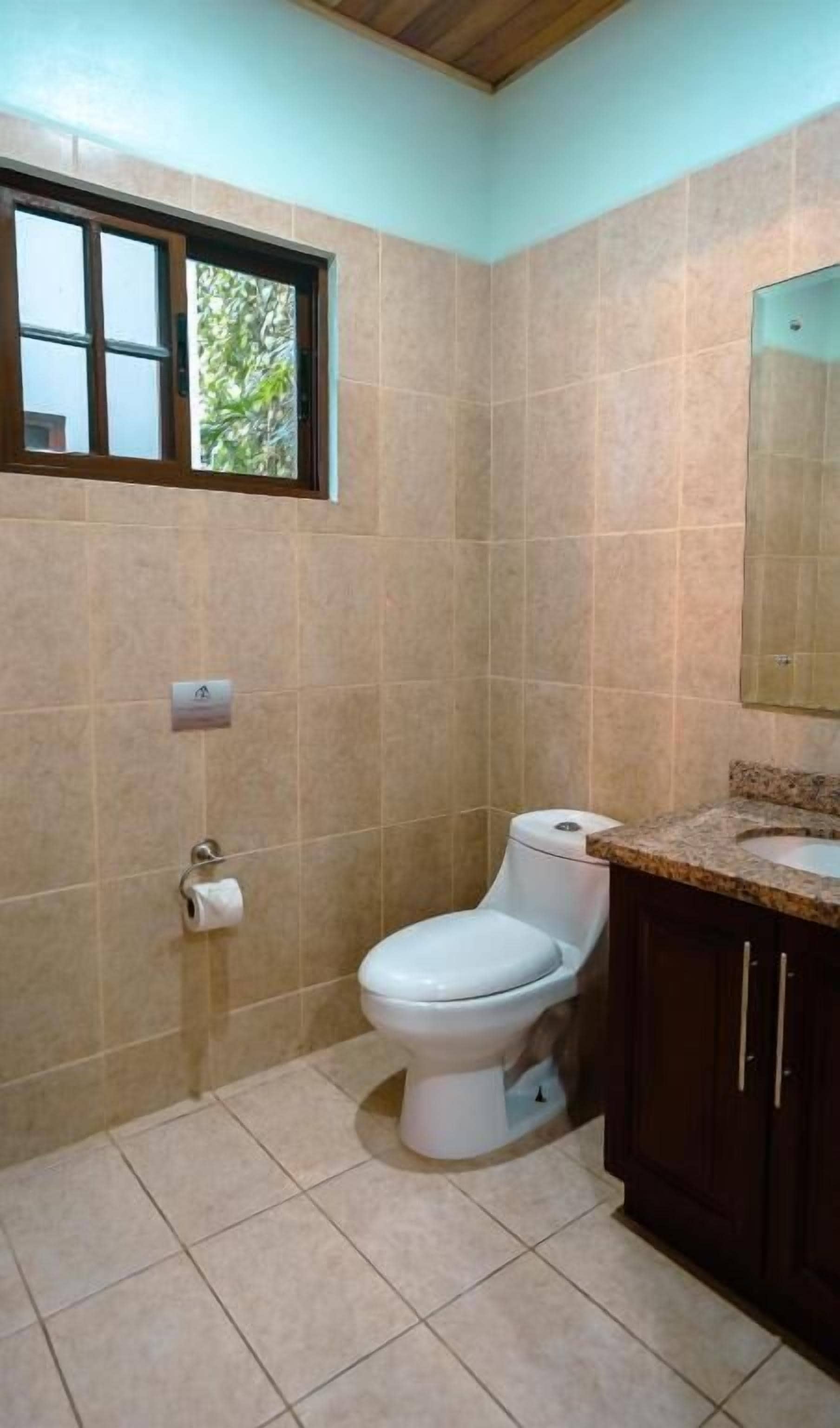 Un baño con inodoro, lavabo y ventana.