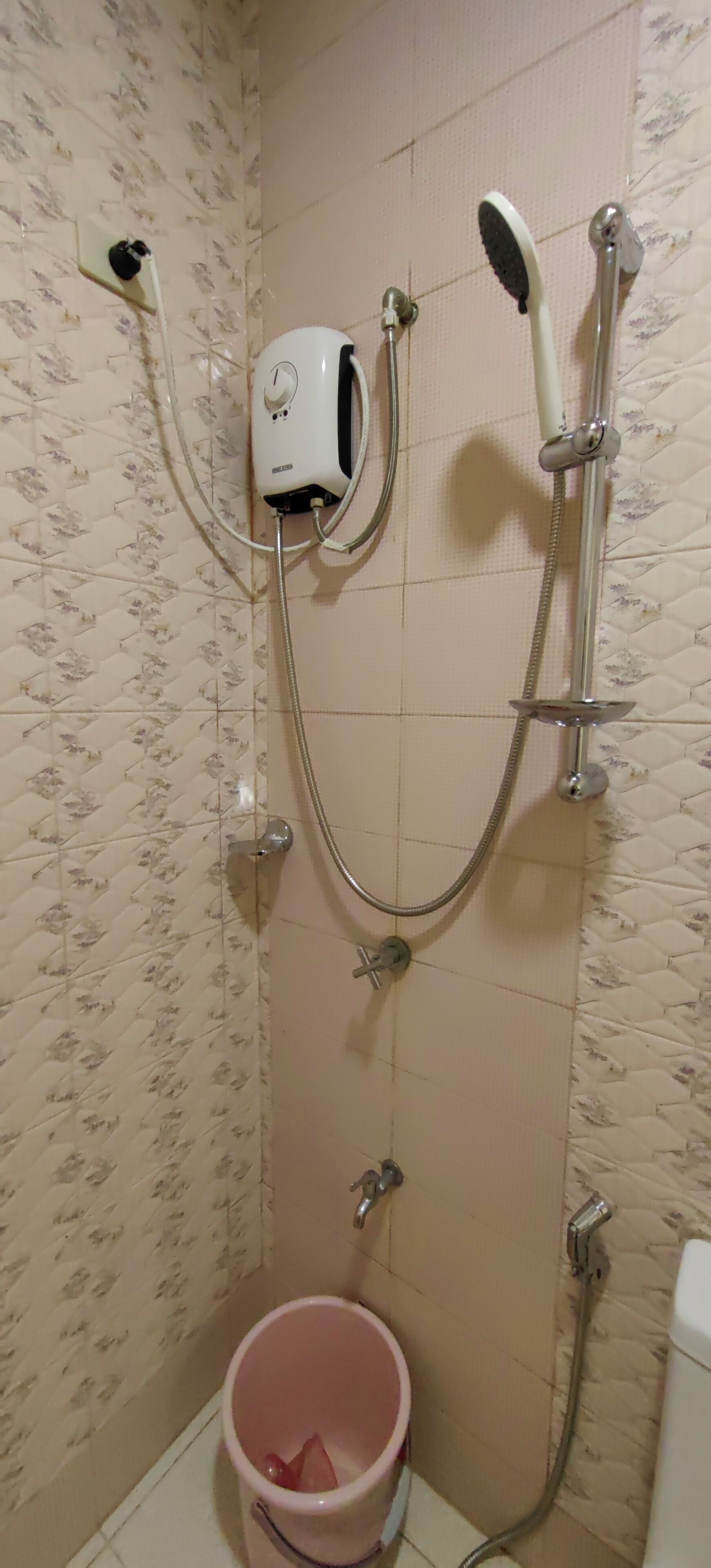 A bathroom with a shower, a toilet, and a bucket.