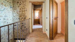 A stone-walled hallway with a wooden staircase and a door leading to another room. - Le Fonti Apartments With Ac Near Siena (Poggibonsi)